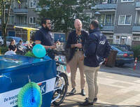 wethouder de vries met bakfiets vol speelgoed in gesprek met mensen van DOCK