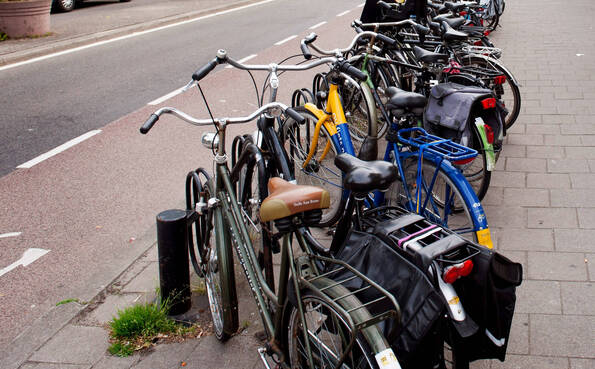 Fietsenrek op de stoep, gevuld met net gestalde fietsen, daarnaast vrije loopruimte