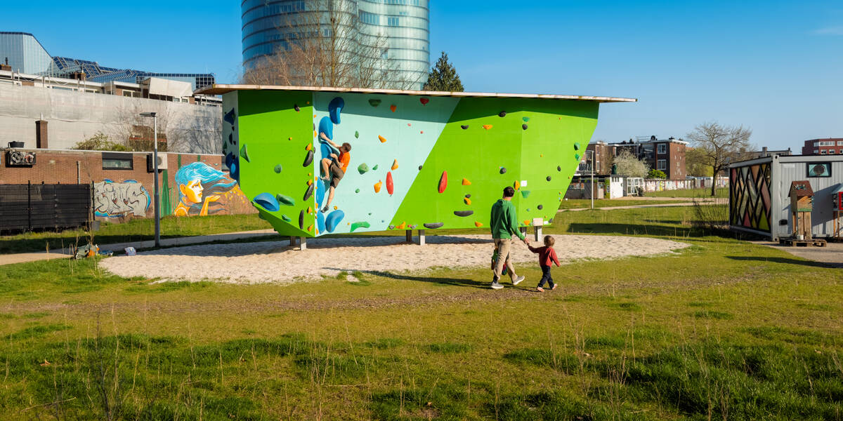 Link naar foto in Flickr: een klimmuurtje bij de Handelkamerstraat, op de voorgrond een man met een klein kind aan de hand.