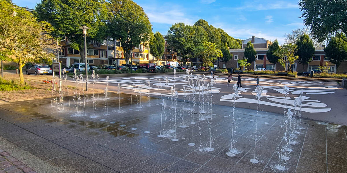 Link naar foto in Flickr: fontein op het Herderplein met op de achtergrond spelende kinderen. 