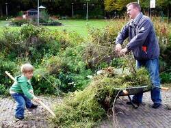 Man en kind met kruiwagen vol groenafval