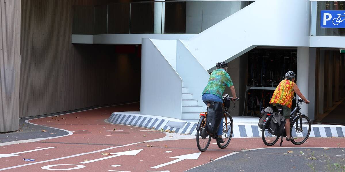 Link naar foto in Flickr: 2 mensen fietsen richting de fietsenstalling bij het station. 