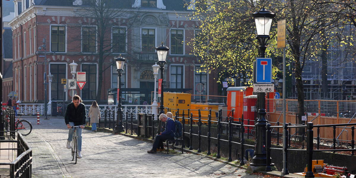 Link naar foto in Flickr: fietser op de Drift en op een bankje zitten 2 mensen in de ochtend zon.