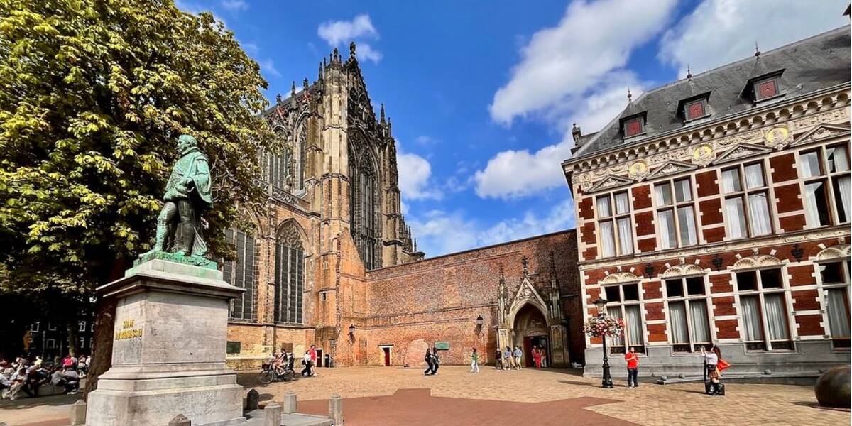 Link naar foto in Flickr: Domplein in de zon met op de voorgrond het beeld van Jan van Nassau en daarachter het Academiegebouw.