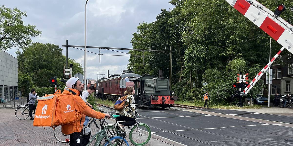 Link naar foto in Flickr: fietsers wachten voor de spoorwegovergang, naast het Spoorwegmuseum. 