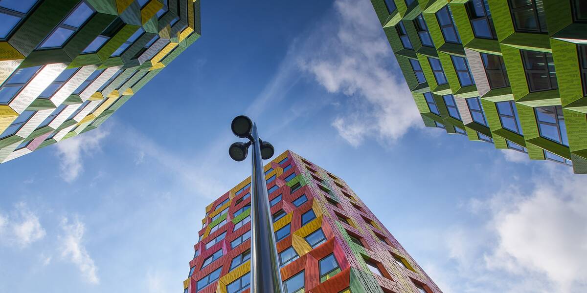 Link naar foto in Flickr: gekleurde hoogbouw De Kwekerij, bezien vanaf onderaanzicht vanaf de grond.